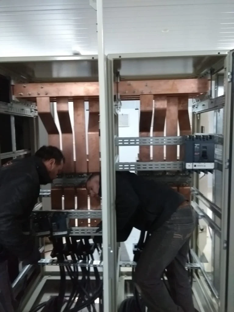 Técnicos montando barras de cobre dentro de un tablero
